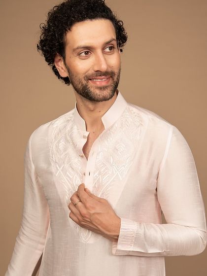 A close-up on the delicate embroidery of the powder pink kurta. The fine threadwork is a hallmark of my commitment to quality and detail.