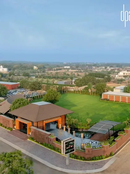 An aerial view of the Dhanshree Farmhouse reveals its expansive layout, with a large event lawn, parking, and the main entrance pavilion.