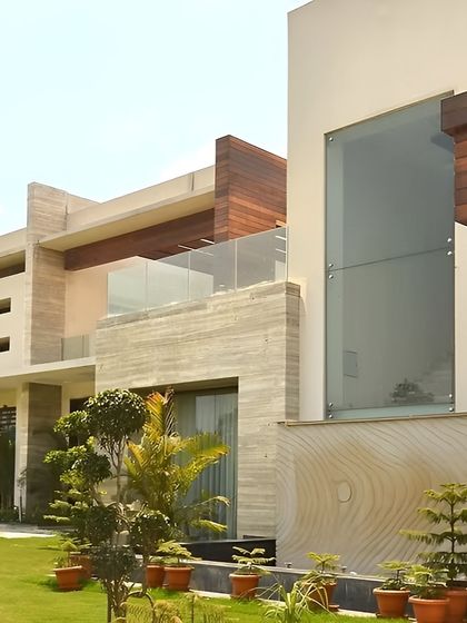 This view highlights the home's integration with its environment. The use of natural stone, wood cladding, and large glass panels creates a dialogue between the structure and the manicured landscape surrounding it.