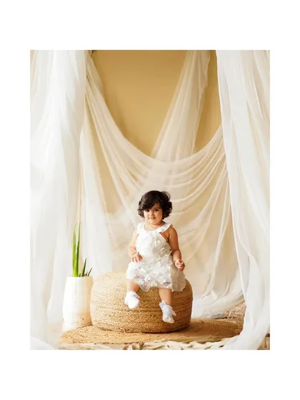 A beautiful solo portrait of a toddler, sitting confidently on a jute pouf. Our sessions always include individual shots of the children to capture their unique stage.
