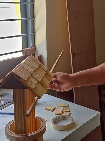 Rajashekhar adding the final touches to the wishing well he built. The roof is carefully tiled with small, individual wooden shingles.