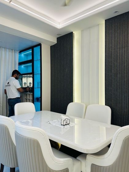 A look at the dining area in the JM Florence project, featuring a white marble-top table and a stylish crockery unit with a blue-lit interior.