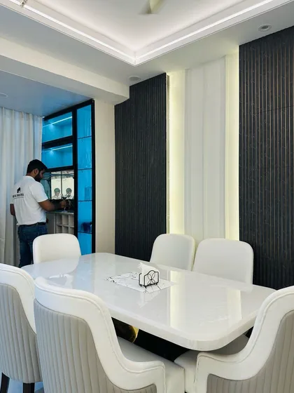 A look at the dining area in the JM Florence project, featuring a white marble-top table and a stylish crockery unit with a blue-lit interior.