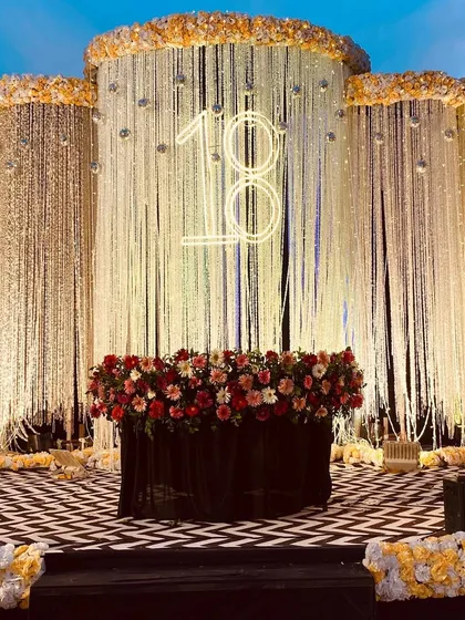 I also design for milestone birthdays. For this 18th birthday party, I created a chic and modern stage with a shimmering crystal curtain backdrop, a custom '18' neon sign, and a bold black-and-white chevron floor for a glamorous celebration.