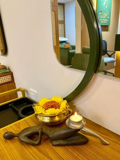 A quiet corner of our sanctuary. A lit candle, fresh flowers in a brass bowl, and a traditional sculpture create a moment of peace.