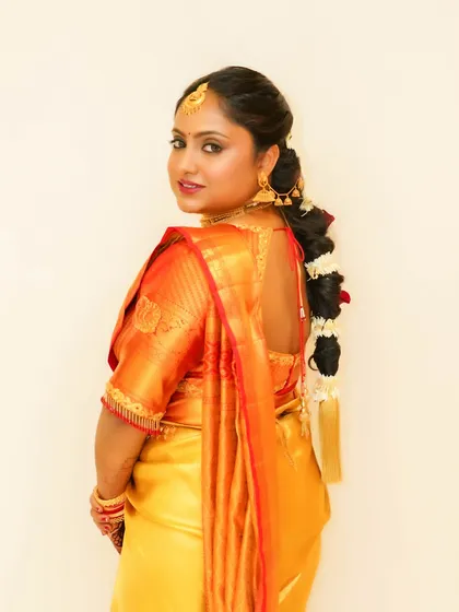 This bride's look features bold, defined eyes and flawless skin, a modern twist on the traditional South Indian style. The makeup is glamorous and confident.