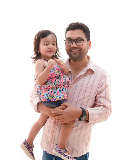 A father's love. This heartwarming shot captures a dad holding his daughter, both sharing a smile, in a simple and clean studio setting.
