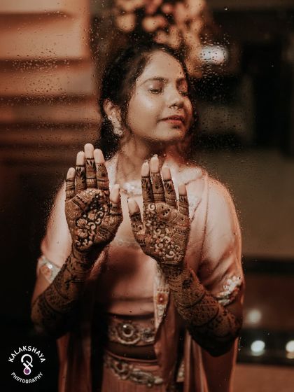 An artistic shot focusing on the bride's beautiful Mehendi design, seen through a window.