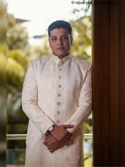 A strong and composed portrait of the groom. The indoor lighting and his direct pose create a formal and sophisticated look, highlighting his wedding attire.