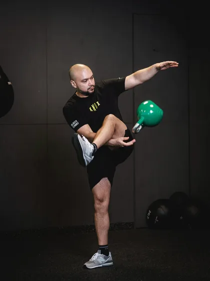 A coach demonstrates an advanced kettlebell flow movement, showcasing the skill, balance, and creativity that can be developed through this training style.