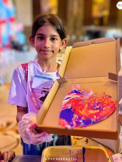 A young girl holds up her beautiful heart-shaped artwork, a fantastic take-home souvenir from one of our art events.