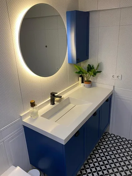 We love adding a pop of color to make a bathroom stand out. This project features a bold blue floating vanity with a sleek, integrated sink. The design is balanced with a modern backlit round mirror for perfect ambient lighting and geometric floor tiles that add personality and character to the space.