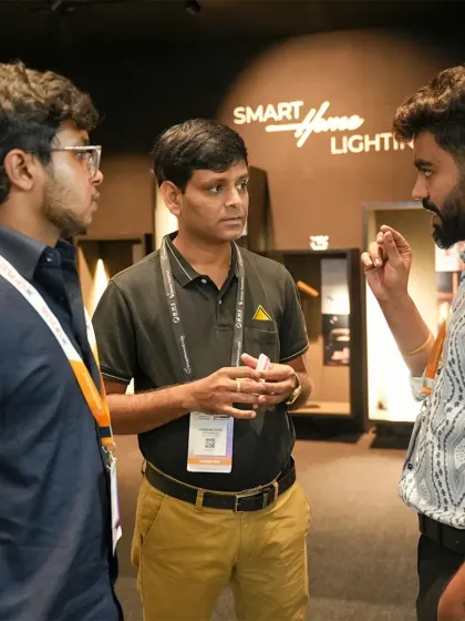 An animated discussion among three attendees in front of a smart lighting display. The expo sparks conversations that lead to new ideas and collaborations.