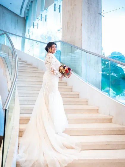 A stunning bridal portrait on a grand, modern staircase. The bride looks absolutely radiant and elegant in this beautiful setting.