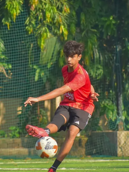A young player demonstrating excellent kicking form during a competitive U15 league game.
