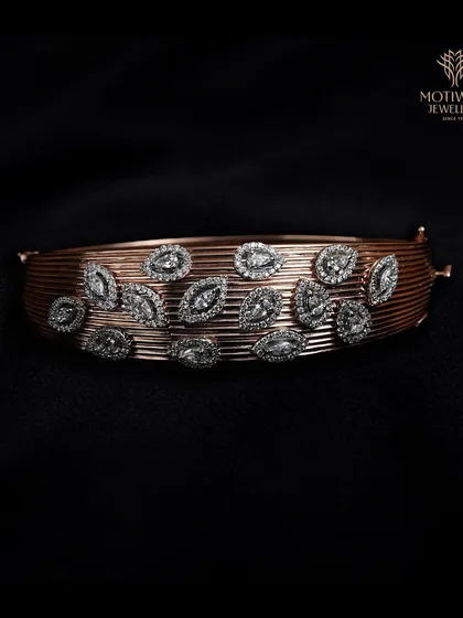 A wide cuff-style bracelet in rose gold, adorned with scattered marquise-shaped diamonds that resemble leaves.