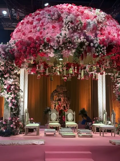 A stunning view of the pink floral dome mandap, with a Shreenathji idol visible in the background. The hanging floral tassels and bells add a traditional touch to this overwhelmingly beautiful and modern mandap design.