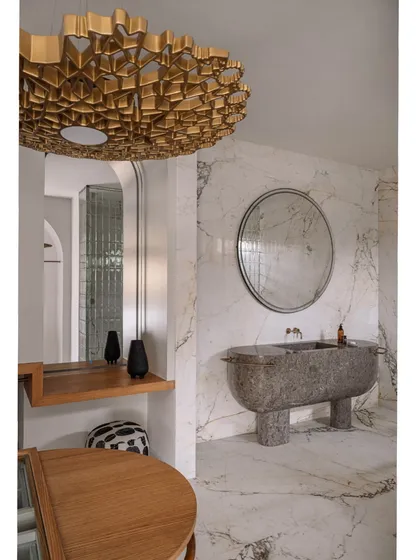 This walk-in wardrobe and bathroom was designed to feel like a high-end SoHo boutique. It features a sculptural, monolithic marble basin, an island dresser, and custom clothing racks, all set against a backdrop of luxurious veined marble.
