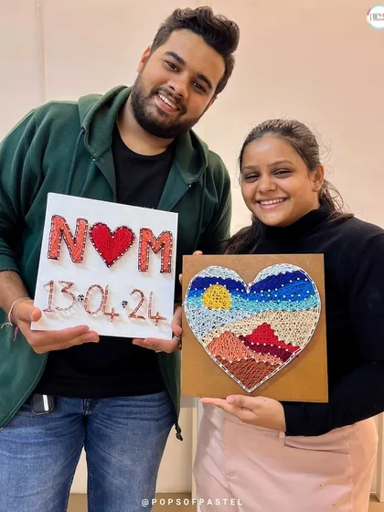 Our studio is the perfect spot for a creative date night. This happy couple proudly shows off the unique string art pieces they made together, a perfect memento of their special evening.