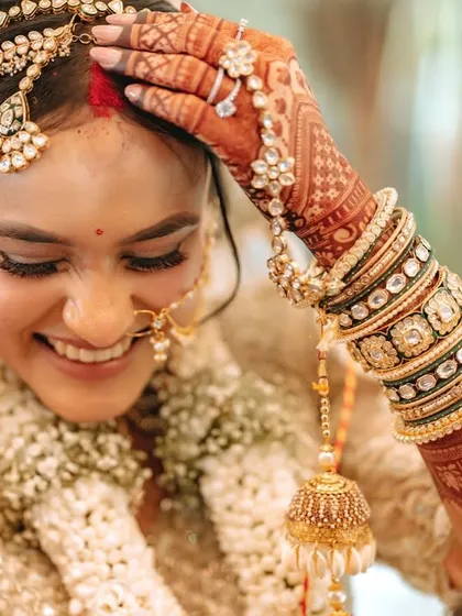 A close-up of the bride's happy smile as she completes the wedding rituals, her hand adorned with beautiful bangles and kalire.