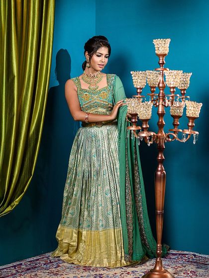 A full-length view of the semi-traditional engagement outfit. The vibrant blue backdrop and green curtain create a rich, color-blocked setting that makes the entire look stand out.