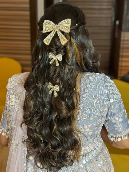 Love is in the hair. A playful and chic Sangeet hairstyle featuring cascading curls and adorable bow accessories.