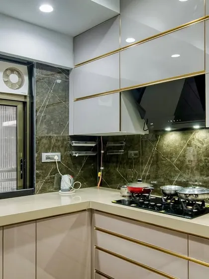 A C-shaped acrylic kitchen with gold profile handles, adding a touch of luxury to the design.
