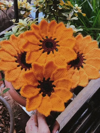 A close-up shot of a handmade sunflower bouquet, highlighting the texture and detail of the crochet work.