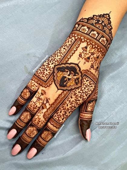 An elegant back-of-hand design featuring a central peacock motif. The surrounding area is filled with a delicate net of vines and flowers, creating a very detailed and beautiful look.