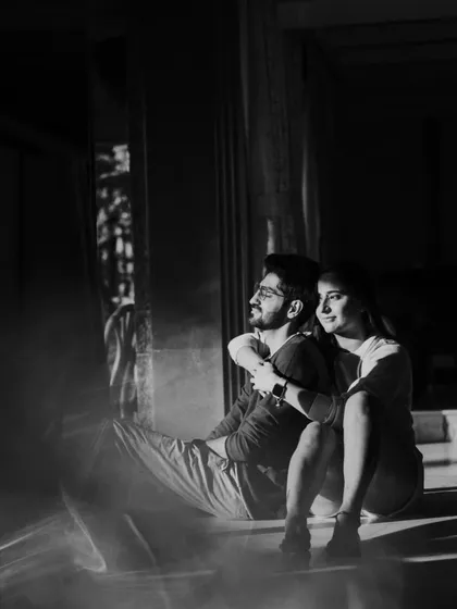 A black and white photo capturing a couple in a quiet moment, with beautiful light creating a soft, reflective flare. This artistic shot showcases our use of natural light to create mood and emotion.