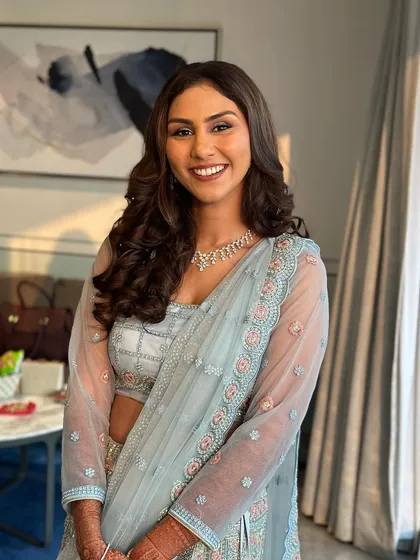 A happy bride ready for her sangeet. The soft curls and side part create a look that is both elegant and easy to wear.