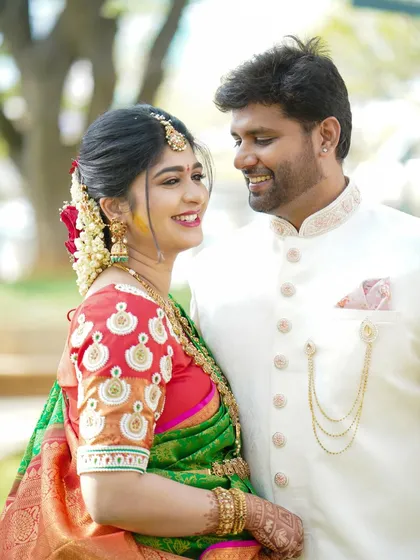 A close-up of a couple sharing a happy moment. The focus is on their expressions and the beautiful details of the bride's saree and blouse.