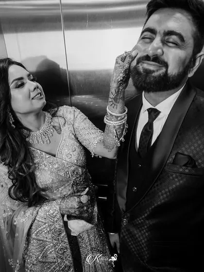 A playful black and white candid of the bride touching the groom's cheek inside an elevator.