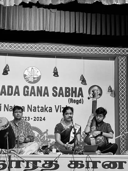 A black and white version of the Narada Gana Sabha stage. The lack of color draws attention to the forms, expressions, and the timeless quality of the music.