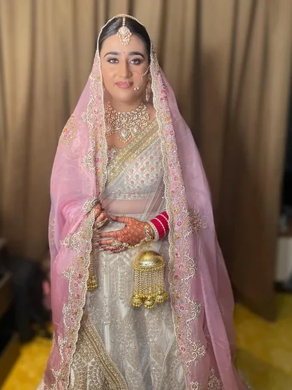 A beautiful bride in a white lehenga with a soft pink dupatta. Her polki necklace and maang tikka add the perfect amount of sparkle to her elegant and understated bridal look.