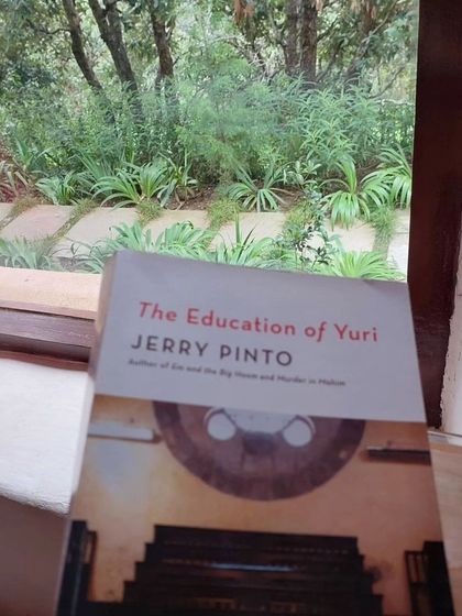 "The Education of Yuri" by Jerry Pinto, another find from our library, set against the lush green backdrop of the retreat.