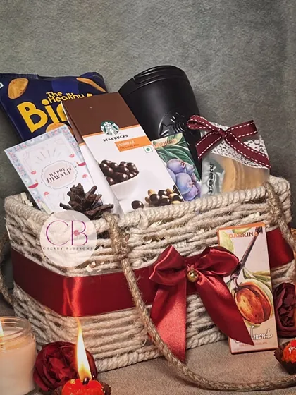 Add a dash of delight to your festivities with our treats. This jute basket hamper is filled with a Starbucks tumbler and chocolates, along with other snacks and our handmade candles.