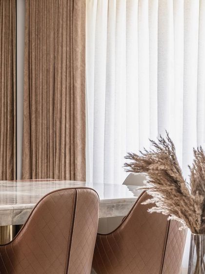 This detailed view captures the soft, vertical folds of the brown and sheer curtains, which provide privacy while gently diffusing natural light, contributing to the room's serene ambiance.