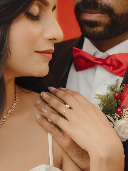 A close-up shot focusing on the bride's hand on the groom's chest, showcasing her engagement ring. A simple, elegant, and meaningful detail photo.