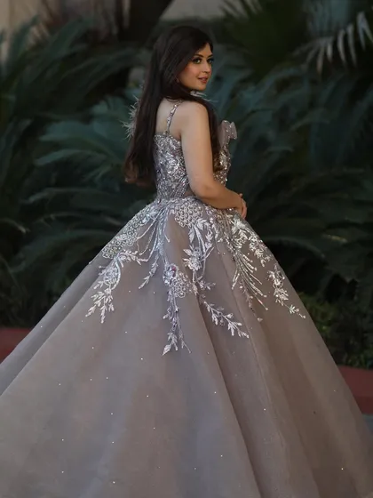 A beautiful shot of our rose gold organza gown from the back. The silver embroidery and feather details create a stunning visual, while the full skirt adds a touch of classic romance.