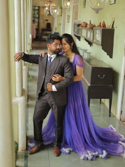 A classic pre-wedding pose in a vintage corridor. The long purple trail of the gown creates a beautiful line, adding to the romantic composition.