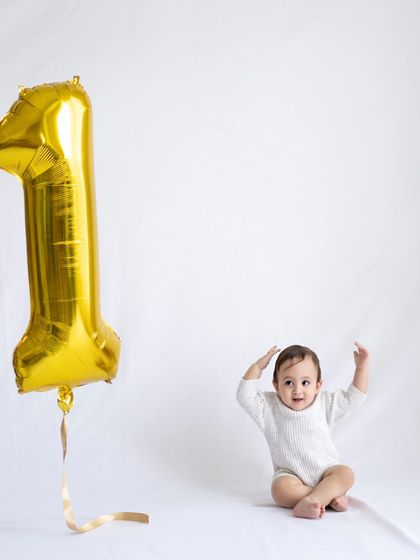 A simple and sweet first birthday portrait with a single gold "1" balloon. Sometimes less is more.