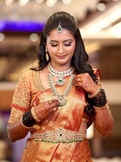 Supriya looked so pretty for her reception. Her makeup features a soft glam eye with a focus on flawless skin, which beautifully complements her orange silk saree and green beaded jewellery.