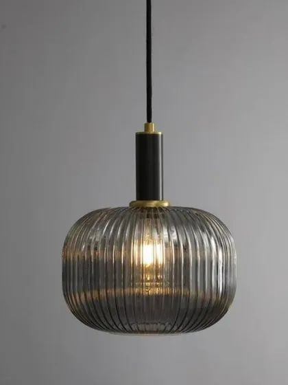 The Cordelia pendant shown in a grey, smoked glass finish with black and brass hardware. This color variation offers a cooler, more contemporary mood while maintaining the elegant ribbed glass texture.