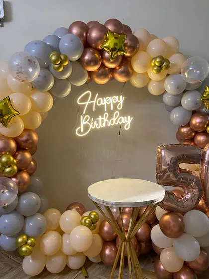 I design elegant backdrops for milestone birthdays, like this 50th celebration setup. This features a full circular balloon arch in a sophisticated rose gold, white, and grey palette, a custom neon 'Happy Birthday' sign, and large foil balloons for the age.