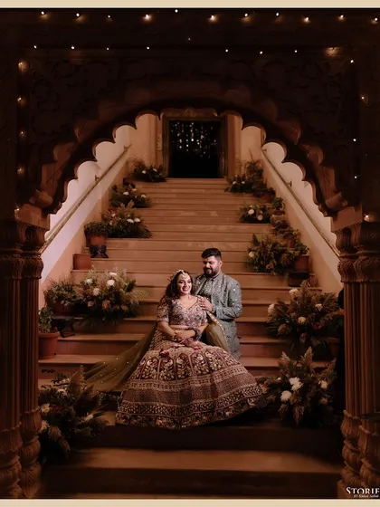 A grand portrait of Sanyukta and Sannidhya on an ornate staircase, the lighting creating a royal and dramatic pre-wedding look.