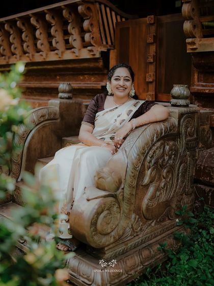 The bride seated on an ornate stone bench, her smile radiant against the backdrop of traditional architecture.