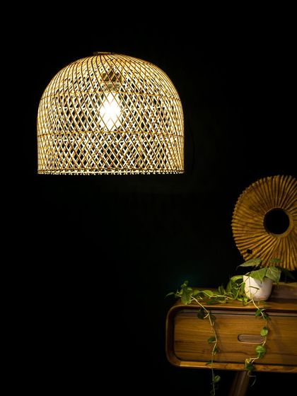A classic dome-shaped rattan pendant, illuminated to create a warm and welcoming pool of light. The open, crisscross weave allows light to spill out, brightening the entire room.