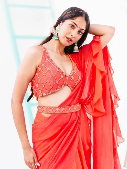Capturing the flow and drape of fabric is essential in fashion photography. This image showcases a ruffled saree, with a pose that emphasizes the garment's movement and lightweight material against a simple, bright background.