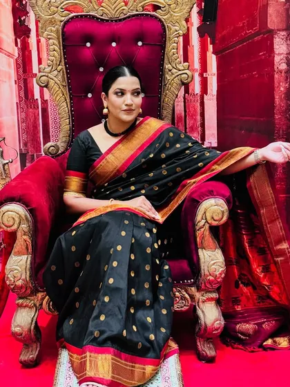 A side profile in the black saree, showcasing the beautiful details of the attire and the regal setting.